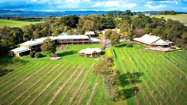 A large estate with multiple buildings, expansive green fields, and a hilly landscape in the background. - Glen Erin At Lancefield - Vineyard Retreat (Lancefield)