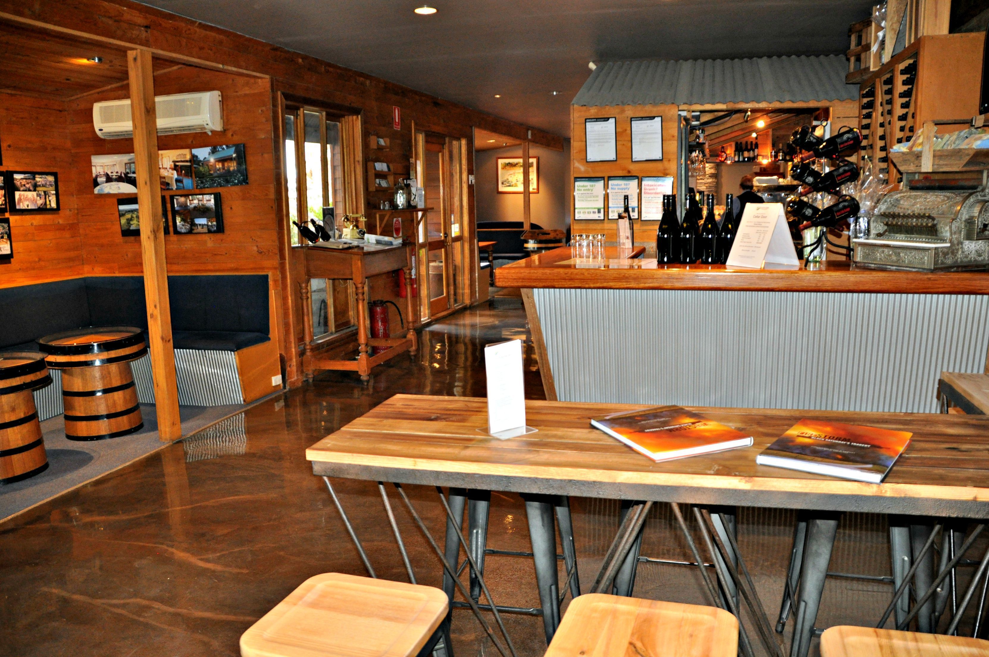 Una zona de bar con muebles de madera, una barra con botellas de vino y un atril para el menú.