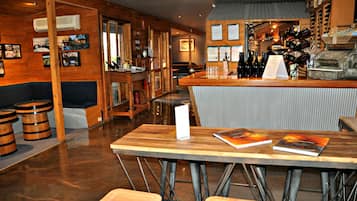 Una zona de bar con muebles de madera, una barra con botellas de vino y un atril para el menú.