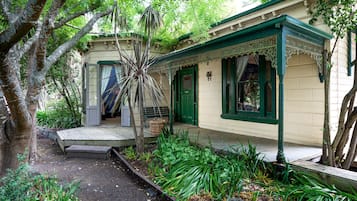 A quaint house with a porch, a small garden, and a wooden deck.
