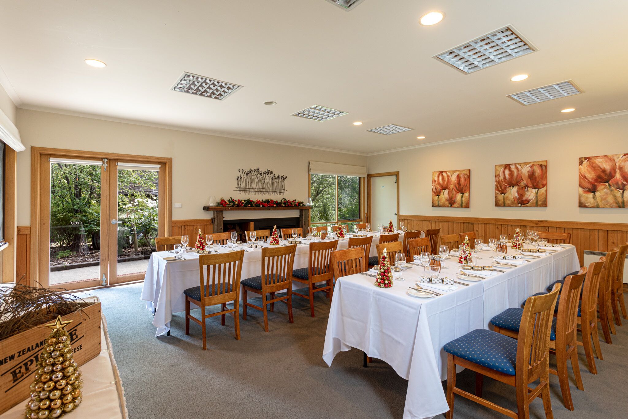 Un comedor con varias mesas dispuestas para una comida, sillas de madera y una chimenea al fondo.