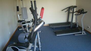 A gym with various exercise equipment including a stationary bike, elliptical, treadmill, and weight machines.