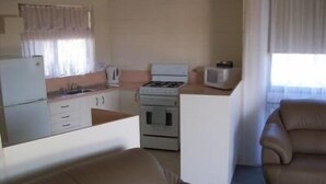 A compact living space with a kitchenette, a sofa, and a window.
