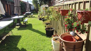 Un jardin avec une pelouse, des tables d’extérieur et des plantes en pot.