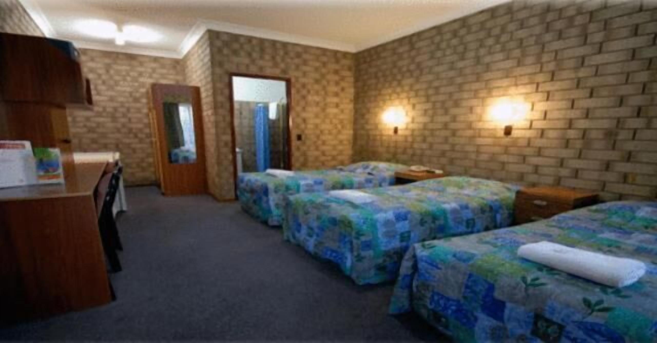 Habitación de hotel con dos camas, un escritorio y un espejo.