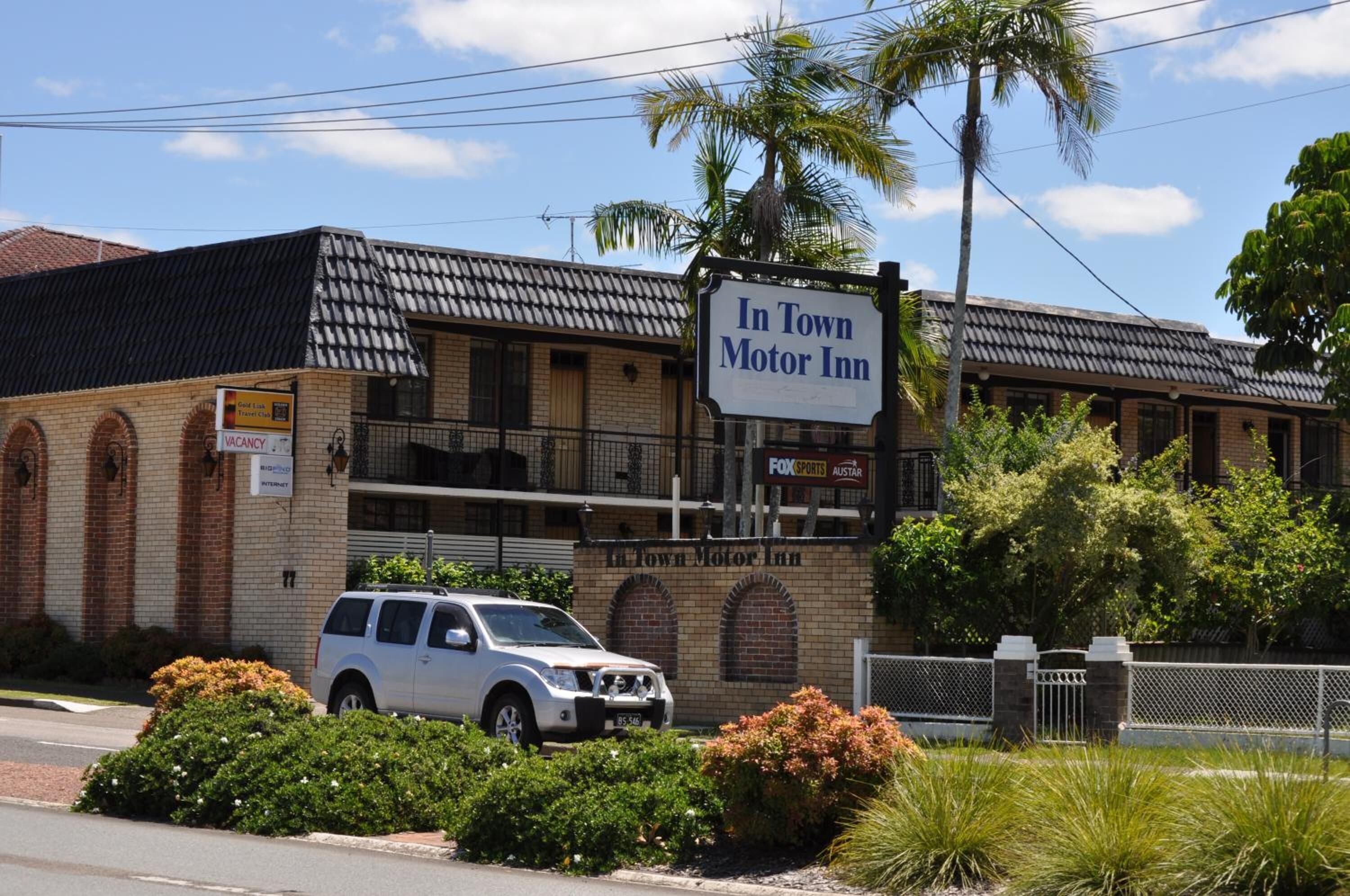 Un edificio con un letrero que dice "In Town Motor Inn" y un SUV estacionado al frente.