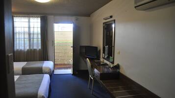 A hotel room with two beds, a desk with a computer, a television, and a large mirror.