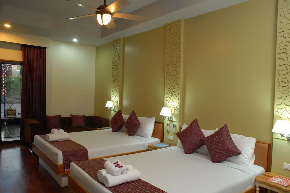 A hotel room with two beds, a ceiling fan, and decorative wall panels.