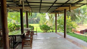 An open-air pavilion with a tiled floor and wooden furniture.