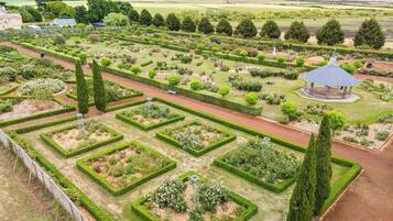 A formal garden with geometric hedges, a central walkway, and a gazebo.