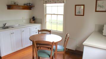 A kitchen with white cabinets, a wooden dining table, and chairs.