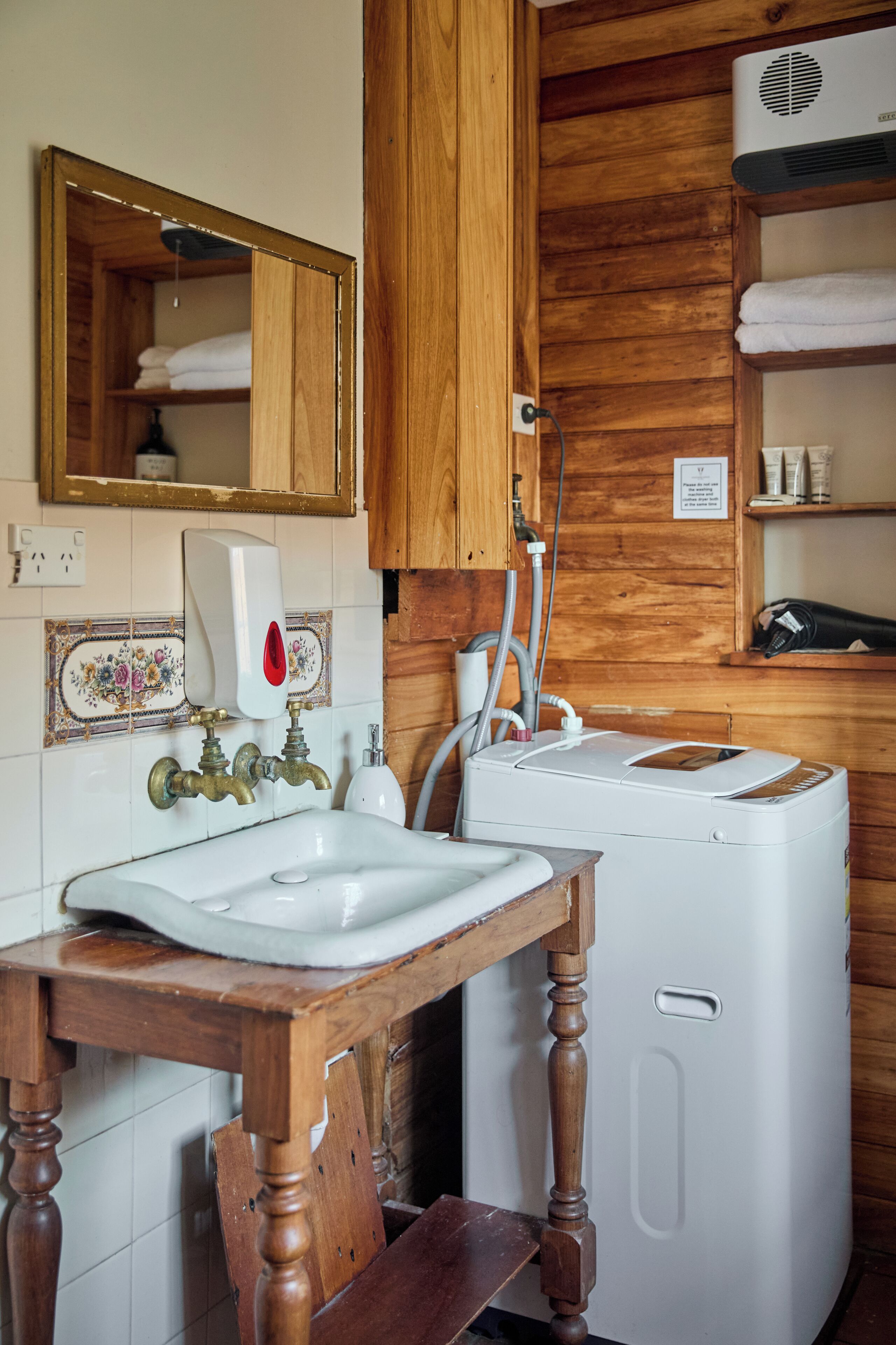 Un mueble de madera con un espejo, un lavabo y una lavadora blanca en un baño.