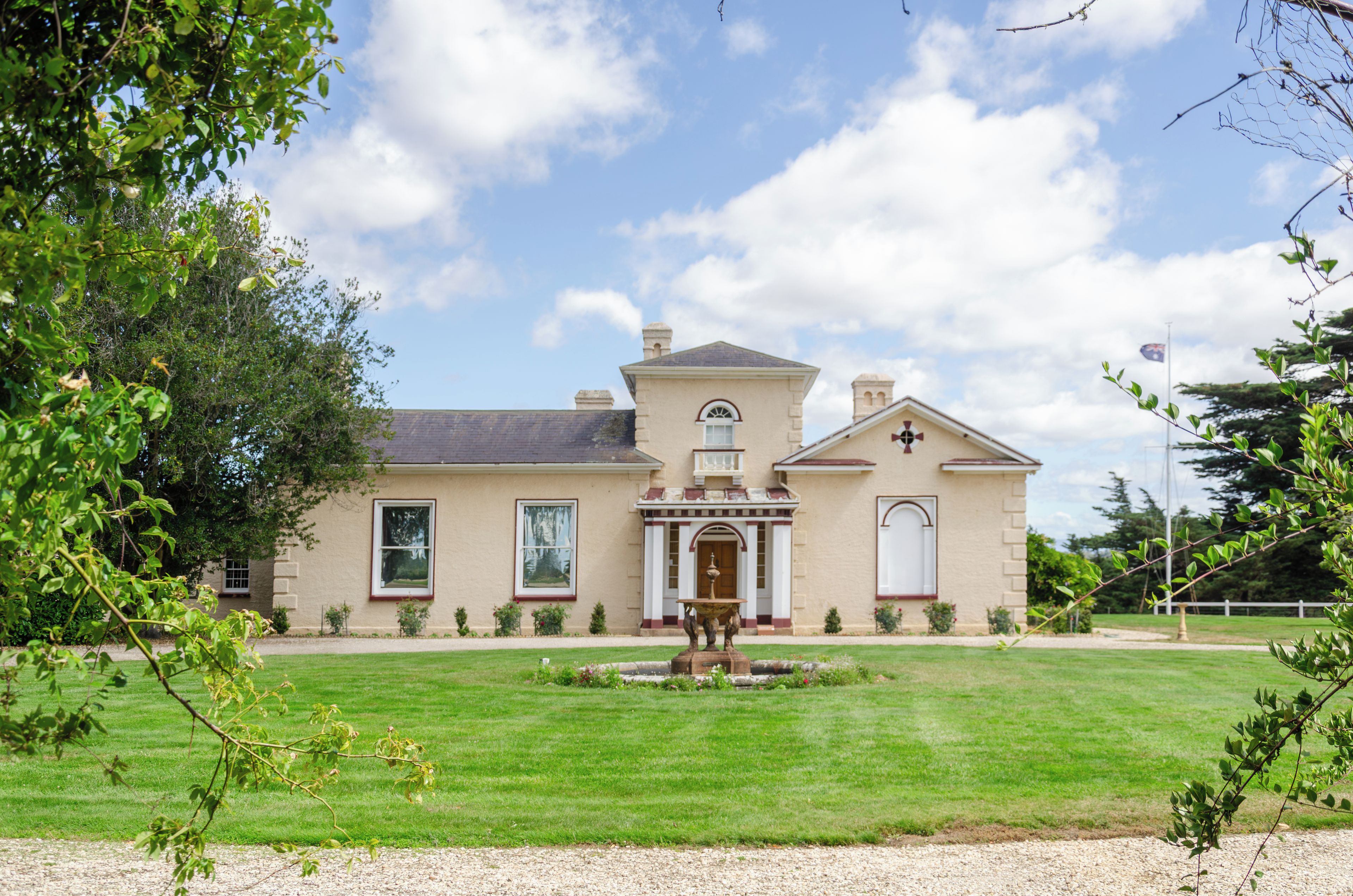 A two-story house with a symmetrical facade, a central entrance with a pediment, and a well-maintained lawn.
