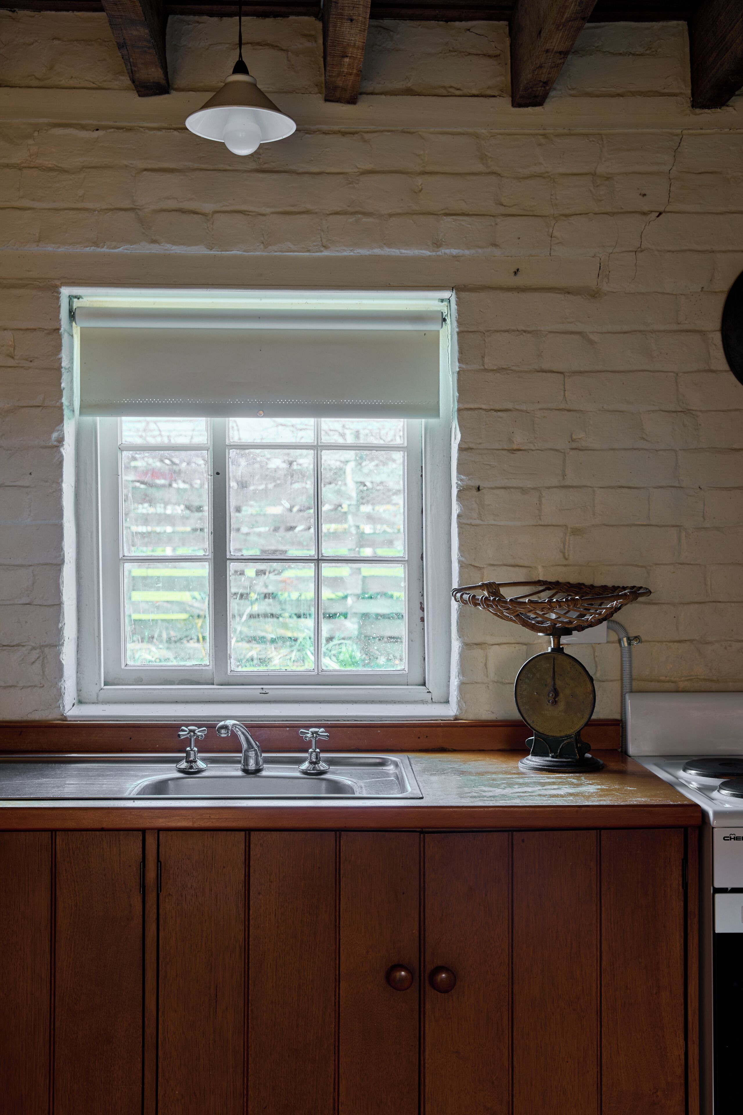 A kitchen with a window, wooden cabinets, a sink, and a scale.