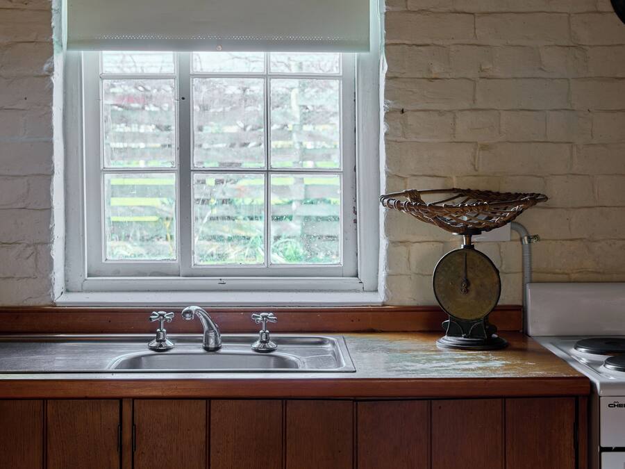 Una cucina con finestra, mobili in legno, un lavello e una bilancia.
