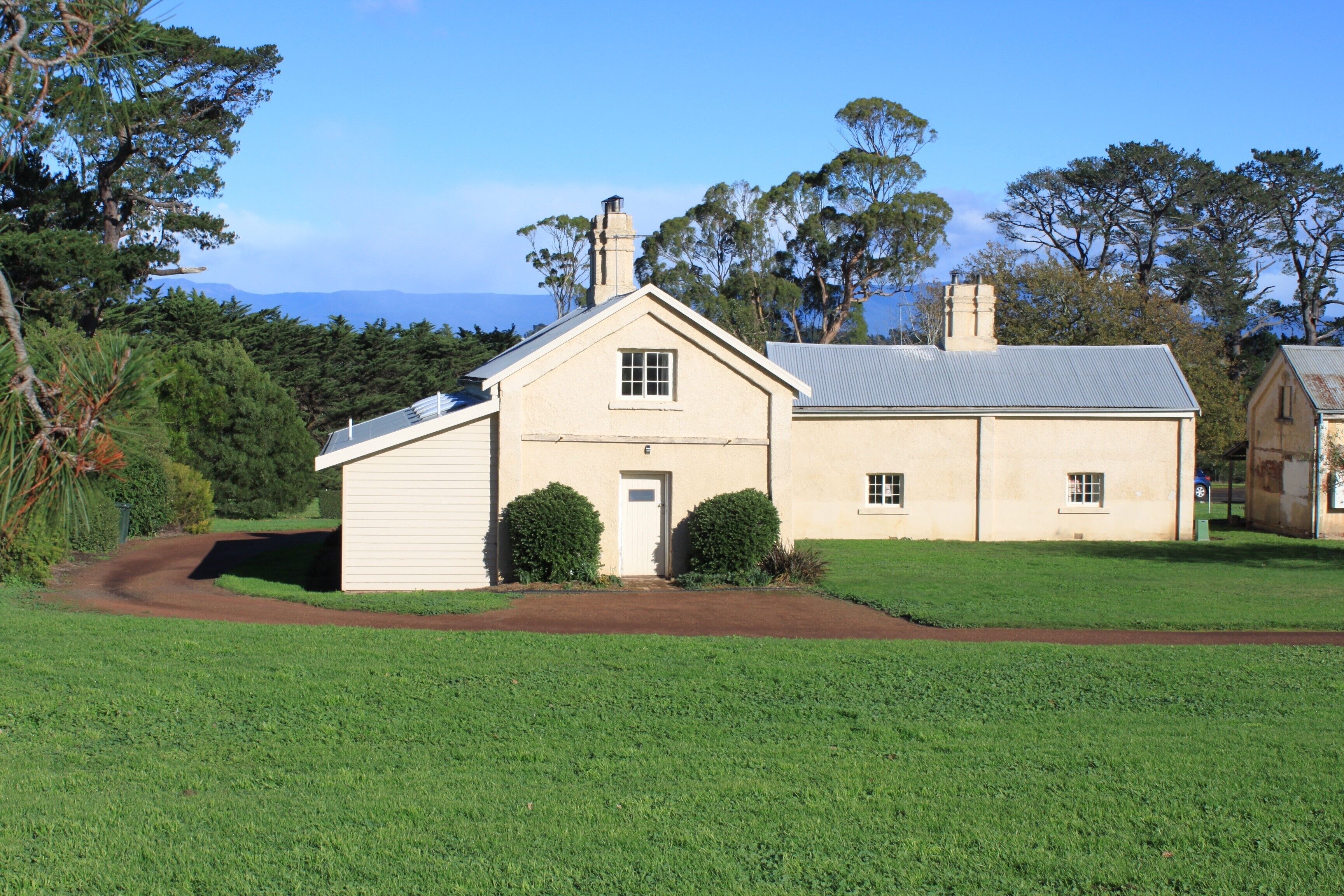 A two-story house with a front yard, a driveway, and a view of the ocean.