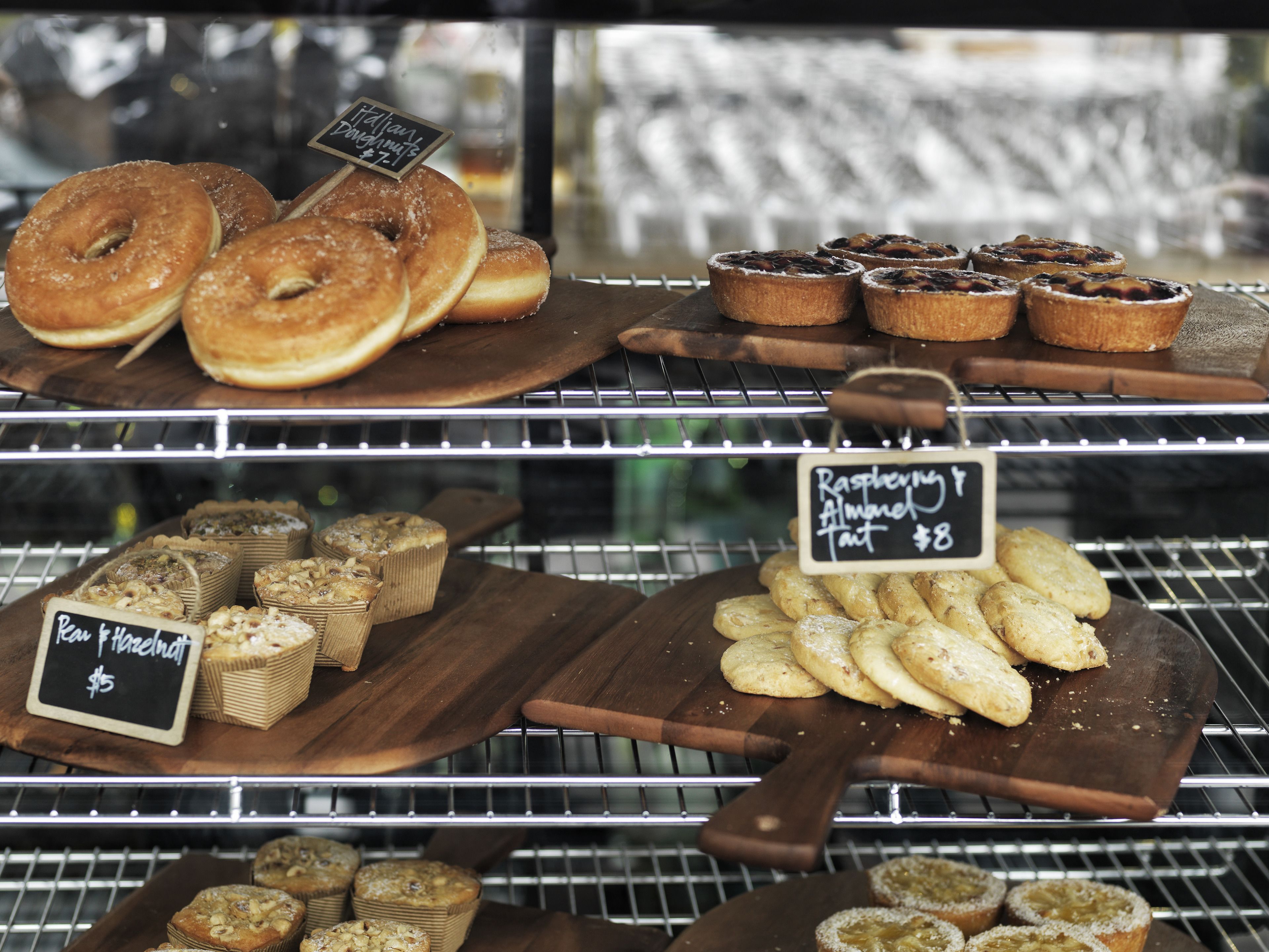 A bakery display with various baked goods like donuts, muffins, and tarts.