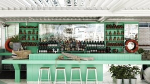 Un espace bar avec des murs verts, une variété de bouteilles et des tabourets.
