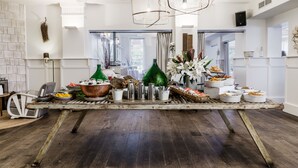 Une cuisine spacieuse dotée d’un plancher en bois rustique, de luminaires suspendus modernes et d’une variété d’ustensiles de cuisine et d’objets décoratifs disposés sur un îlot central.