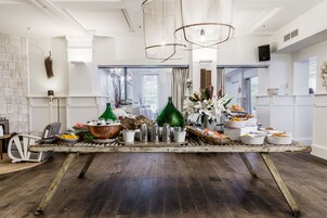 Une cuisine spacieuse dotée d’un plancher en bois rustique, de luminaires suspendus modernes et d’une variété d’ustensiles de cuisine et d’objets décoratifs disposés sur un îlot central.