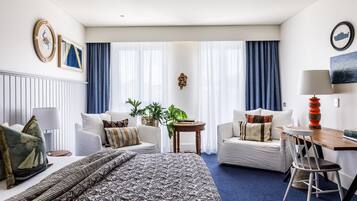 Ein modernes Hotelzimmer mit einem großen Bett, zwei weißen Sofas, einem Holztisch und einem Schreibtisch.