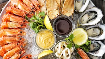 A seafood platter with shrimp, crab, oysters, and lemon slices on a wooden table.