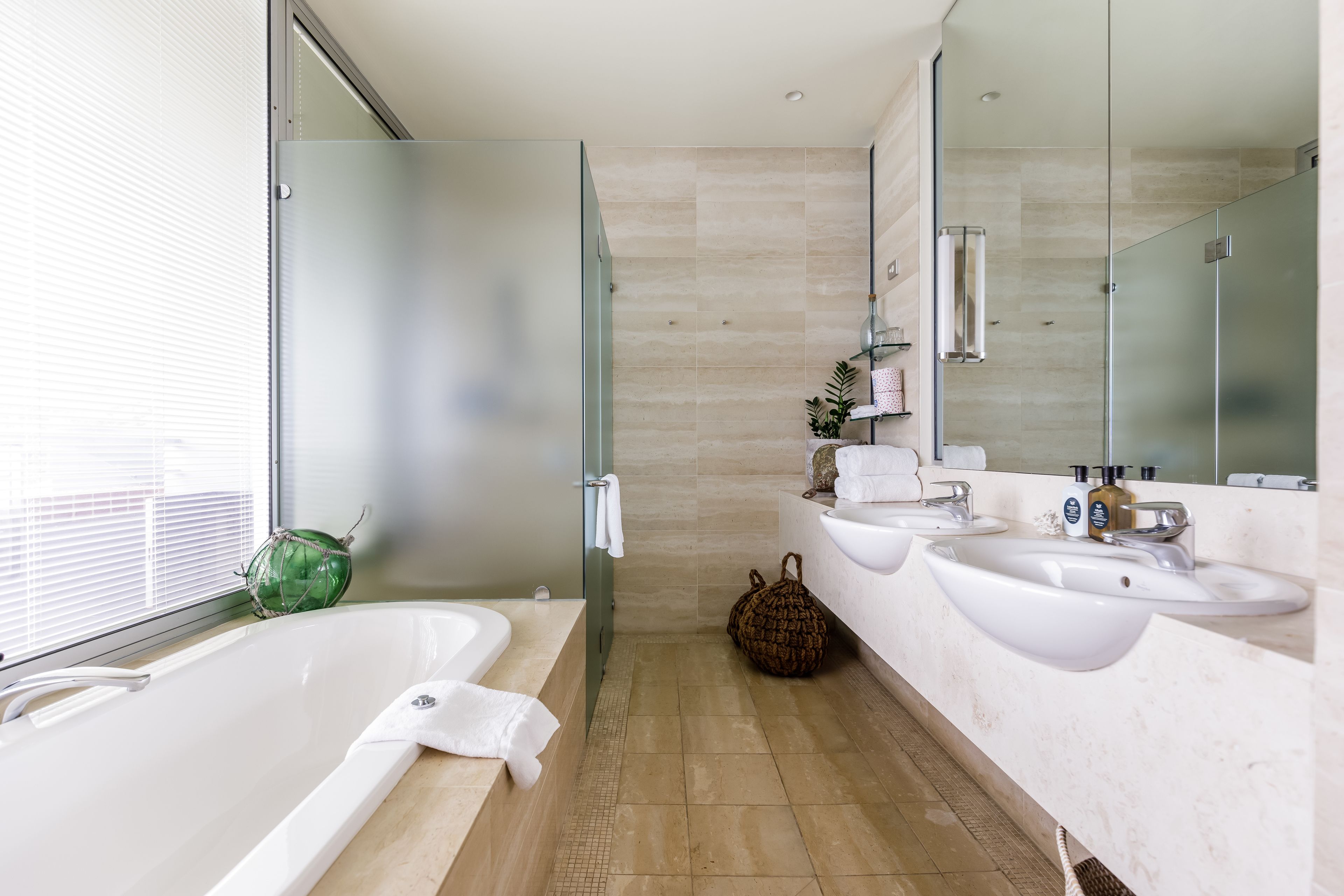 Un baño moderno con una bañera grande, dos lavamanos y una cabina de ducha de vidrio.
