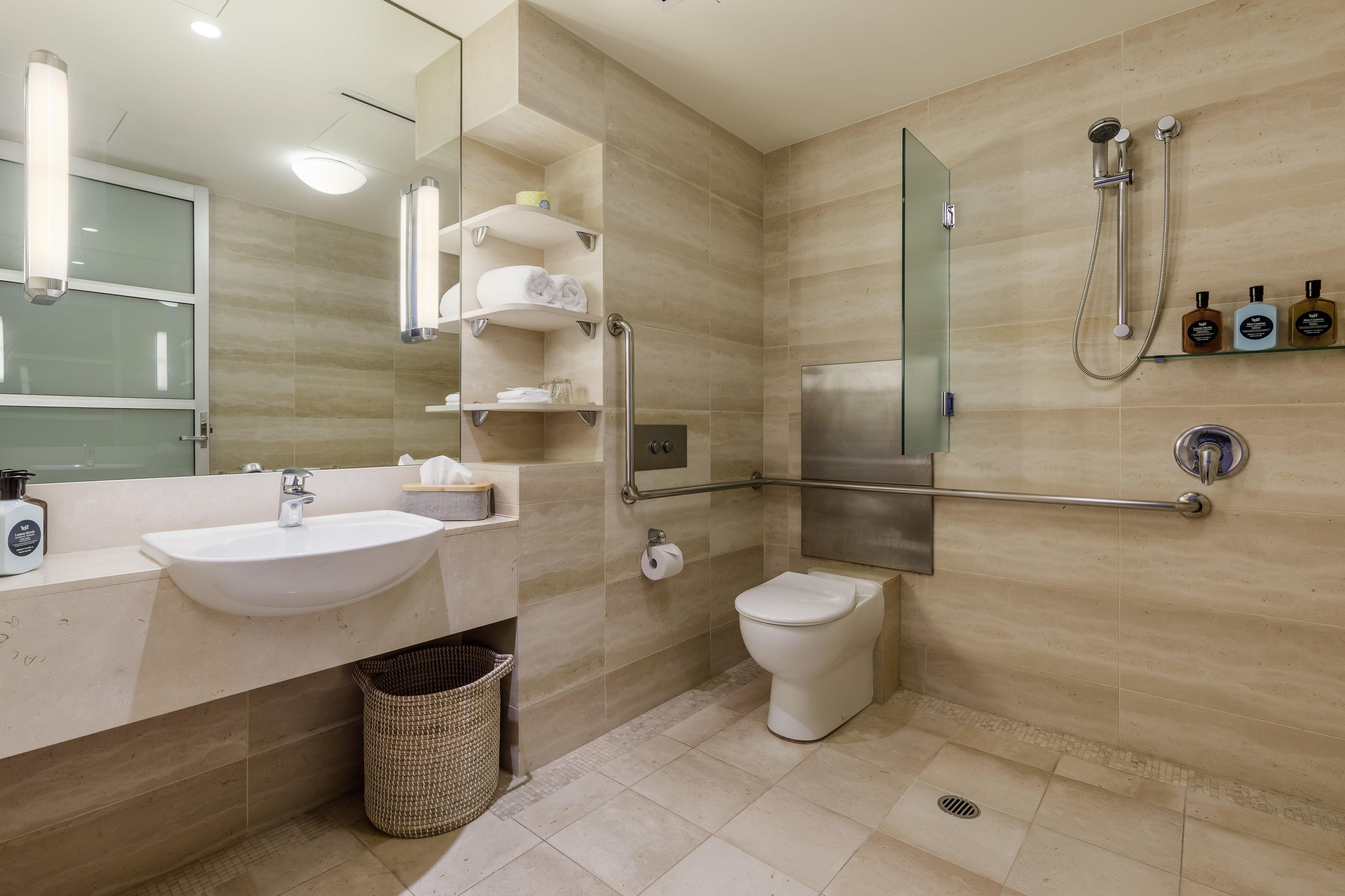 Une salle de bain moderne équipée d’un lavabo, d’un miroir, de toilettes et d’une douche.