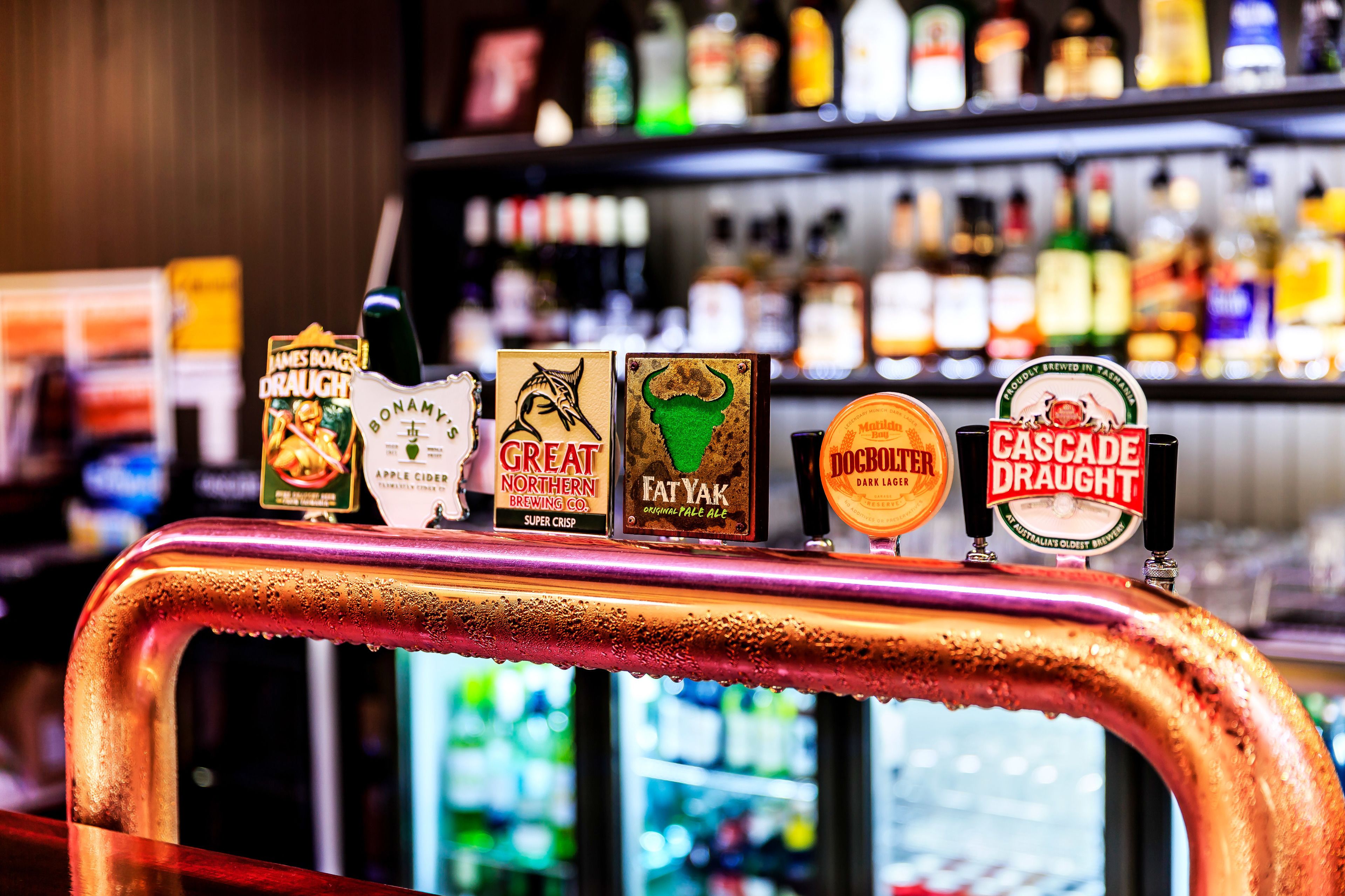 Un bar con varias griferías de cerveza, incluyendo marcas como Great Northern Brewing Co., Fat Yak y Cascade Draught.