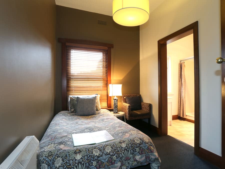 A bedroom with a bed, a chair, a lamp, and a door.