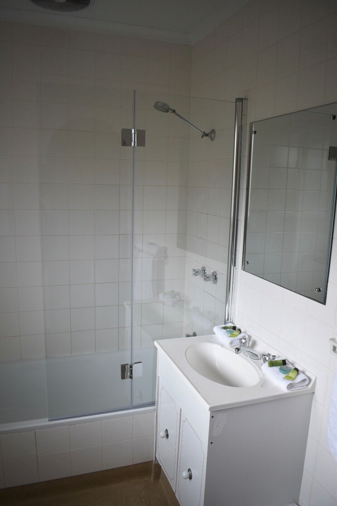 Ein Badezimmer mit einem weißen Waschbecken, einem Spiegel und einer Dusche.