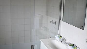 Ein Badezimmer mit einem weißen Waschbecken, einem Spiegel und einer Dusche.