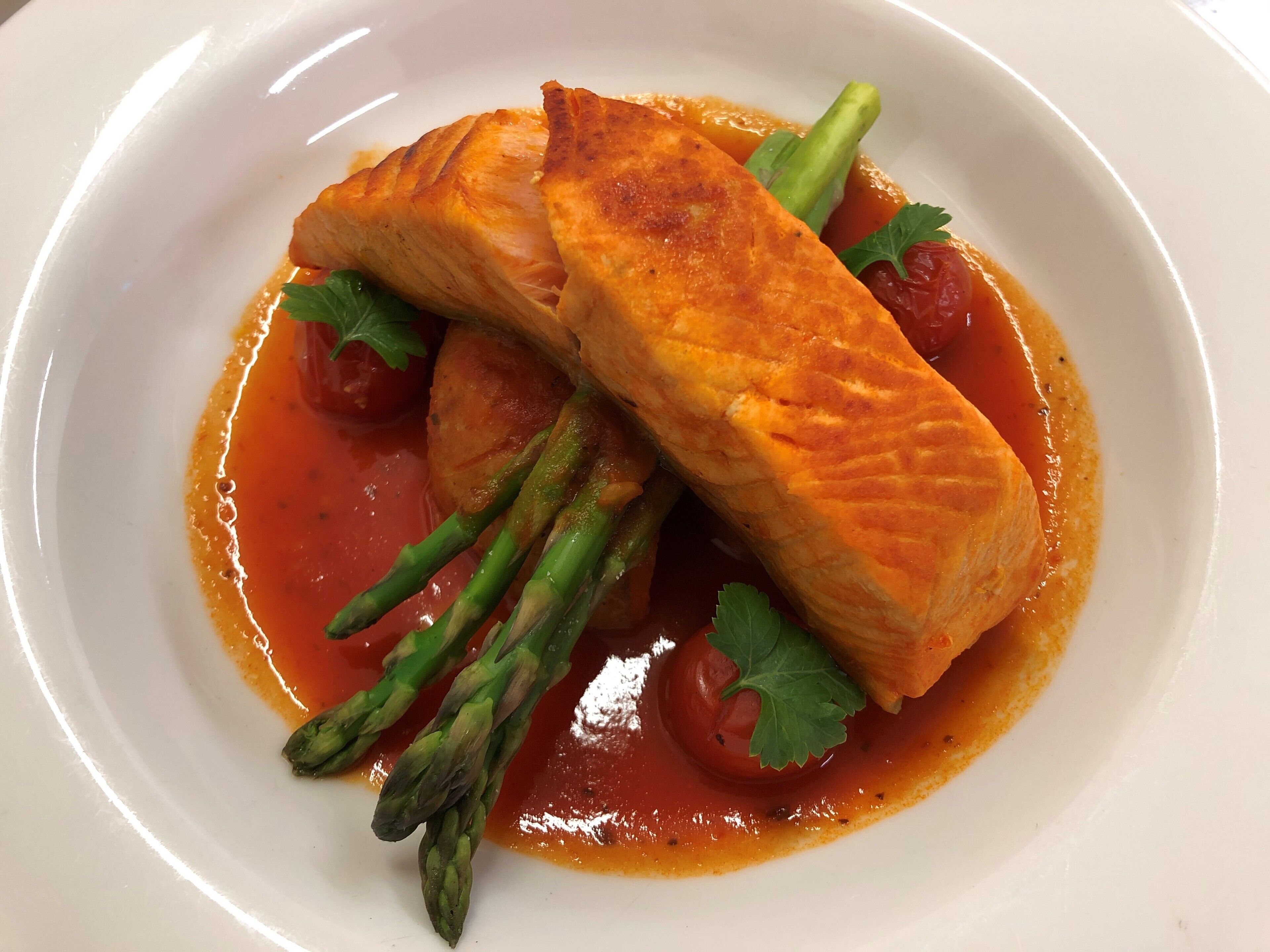 A plate of food with salmon, asparagus, and cherry tomatoes.