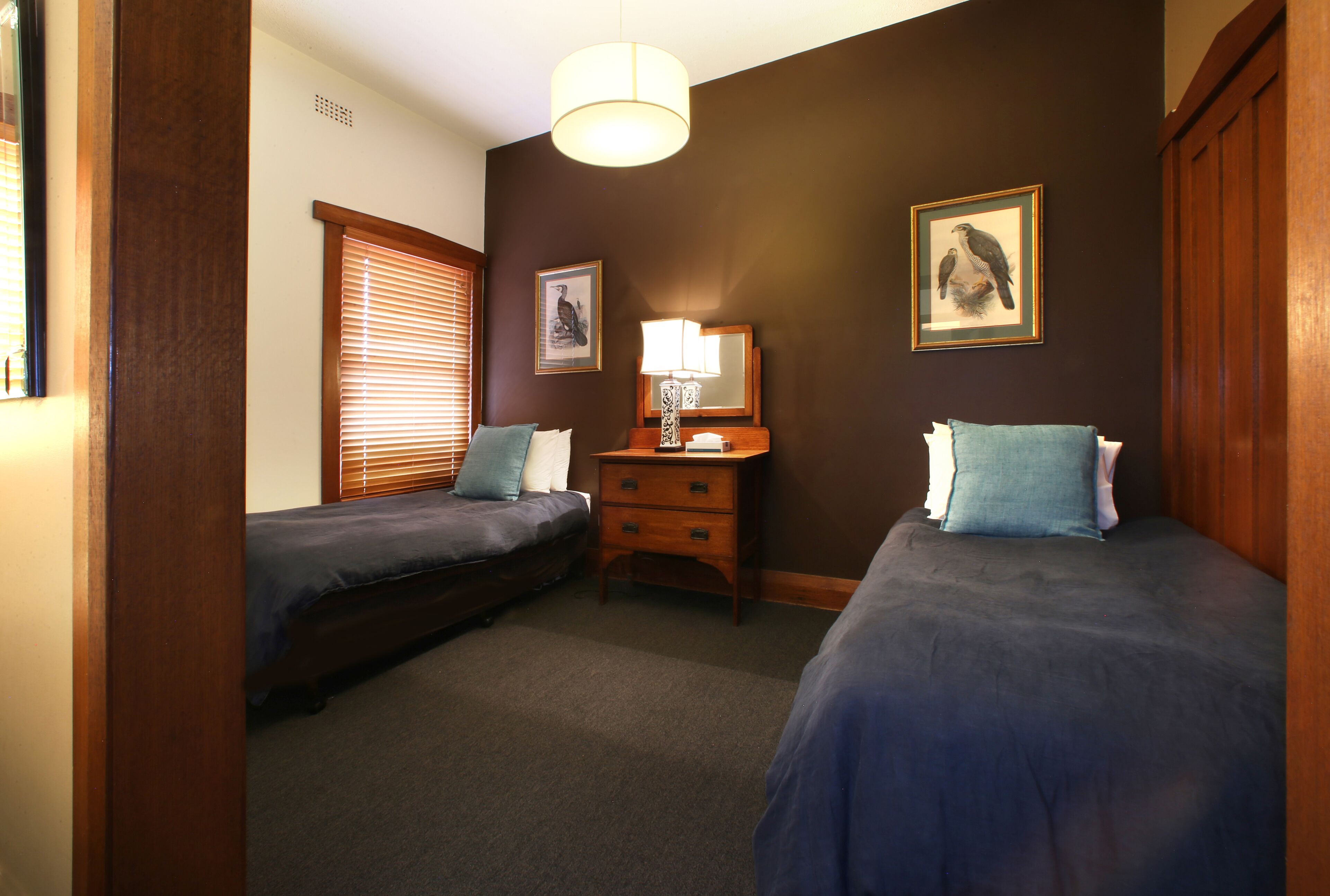 A bedroom with two single beds, a nightstand with a lamp, and a dresser.