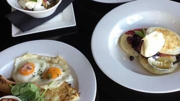 A table with four plates of breakfast food, including eggs, toast, and a bowl of beans.