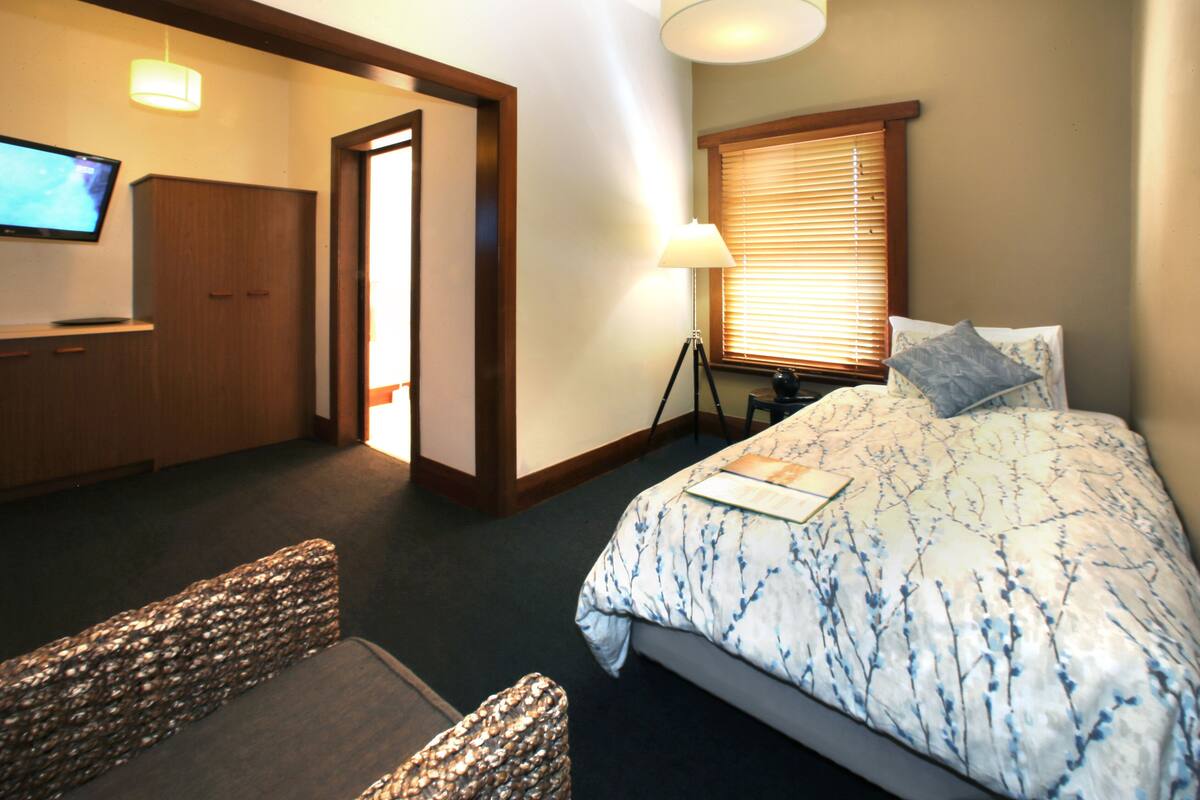 A hotel room with a bed, a desk, a television, and a lamp.