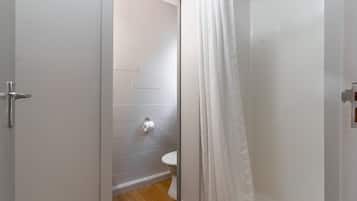 Een badkamer met toilet, douchegordijn en een witte deur.