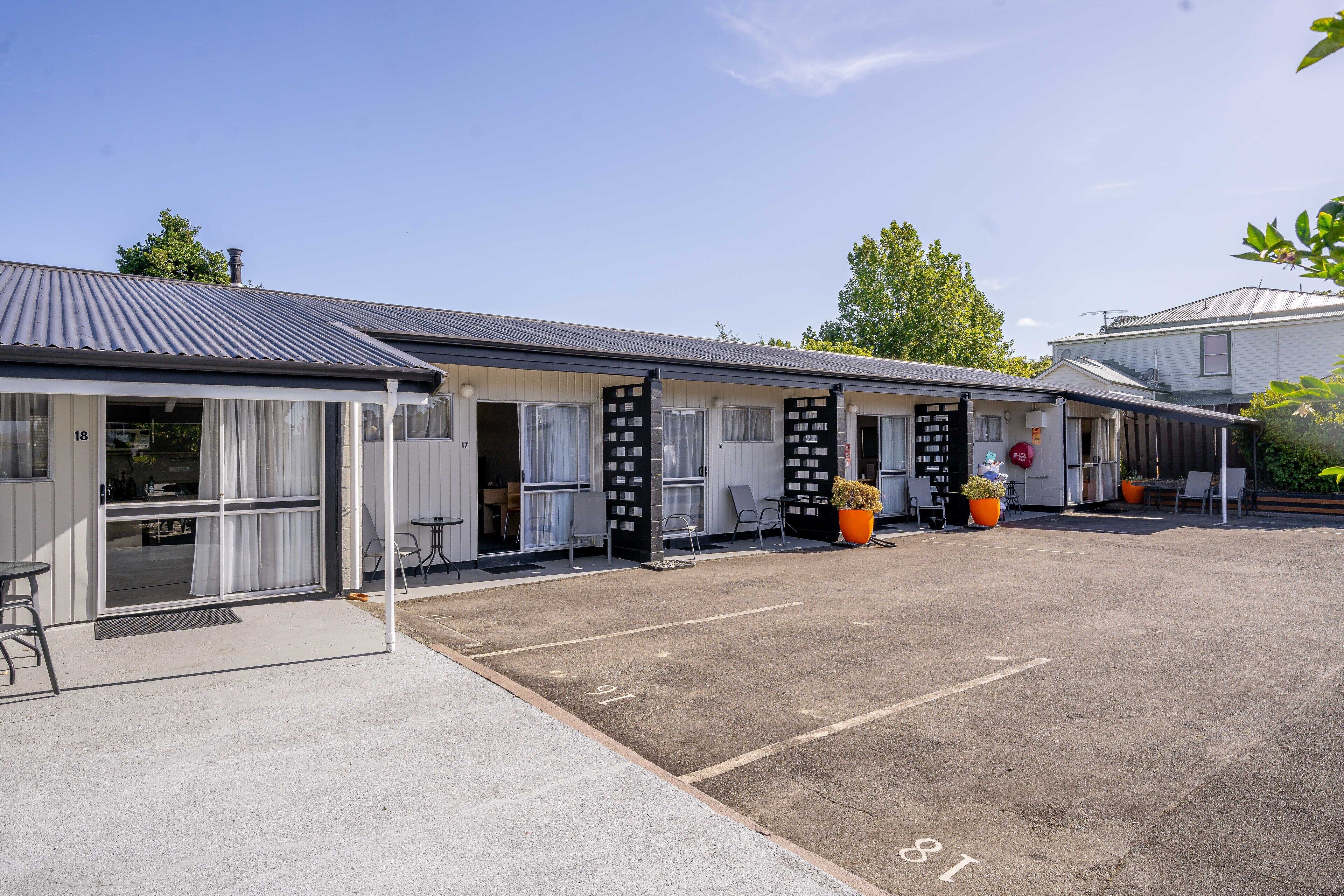 A motel with a parking lot, numbered parking spaces, and outdoor seating areas.