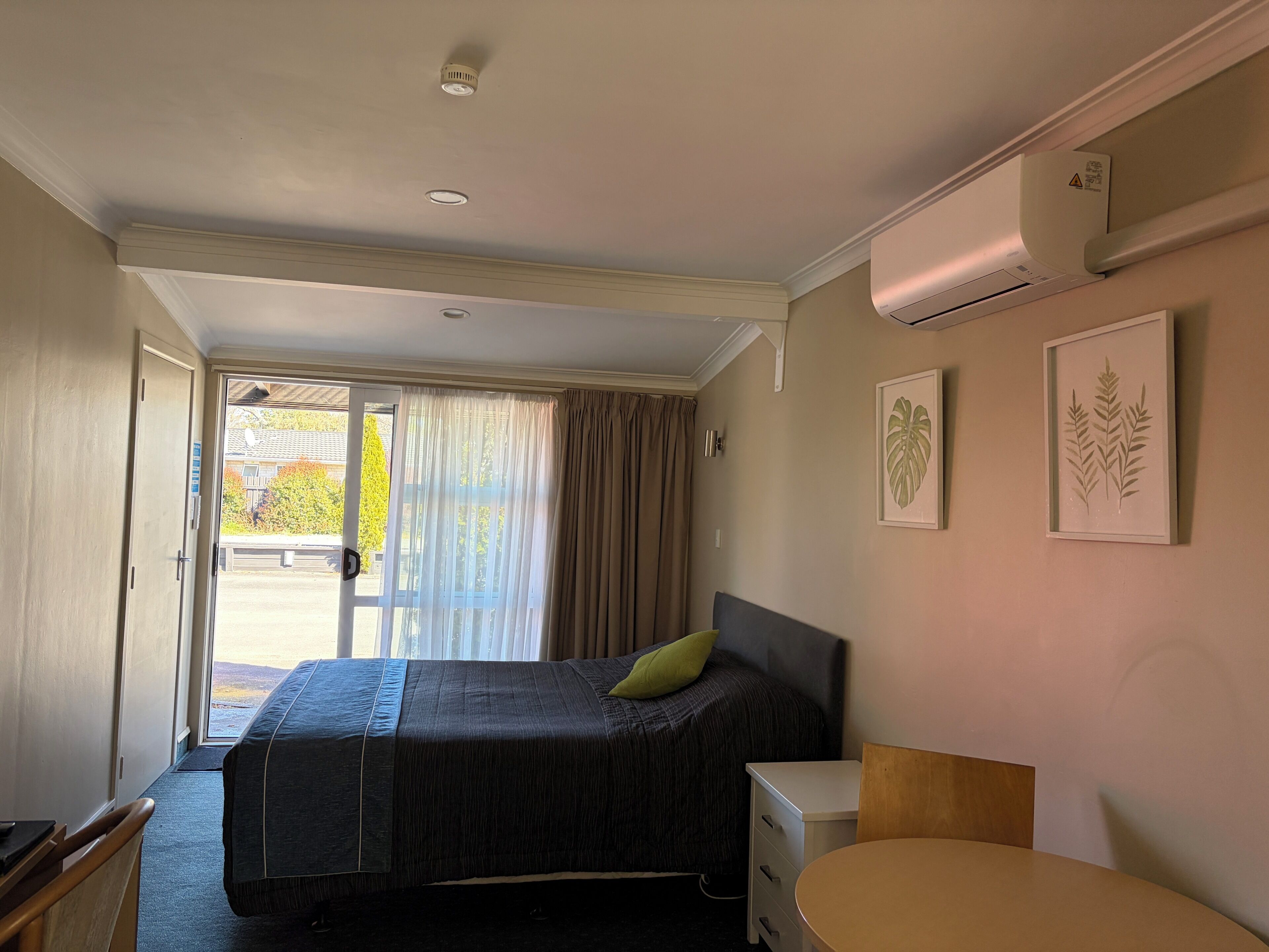 Una habitación de hotel con cama, mesita de noche y vistas a través de la puerta.