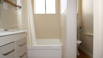 A small, clean bathroom with a shower, toilet, and a vanity with drawers.