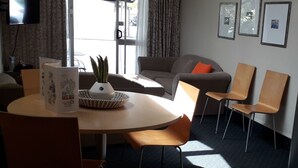 A modern living room with a round table, two sofas, and a TV mounted on the wall. - Amble Inn Motel - Masterton (Masterton)