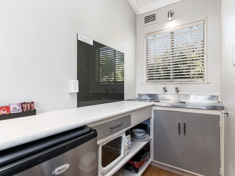 A compact kitchen with a microwave, sink, and storage cabinets.