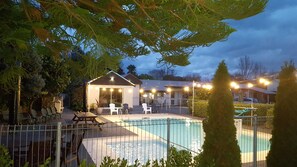A pool area with lounge chairs and a covered seating area.