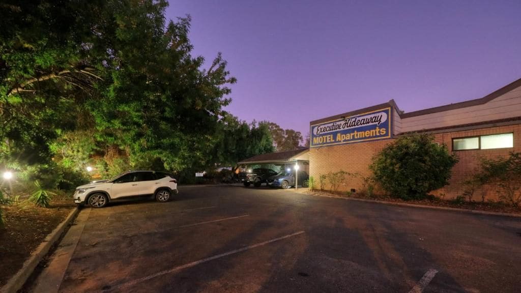 A motel with a signboard, a parking lot, and a building entrance.
