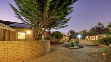 A courtyard with a brick wall, a tree, and a bench.