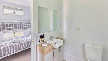 A modern bedroom with a bunk bed, a small sink, and a toilet.