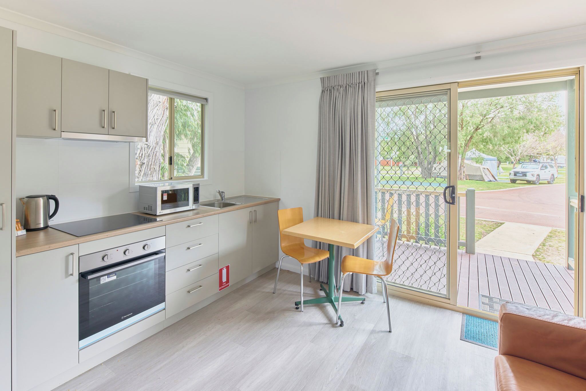 A modern kitchen with a dining area, a large sliding glass door to a deck, and a view of the outdoors.