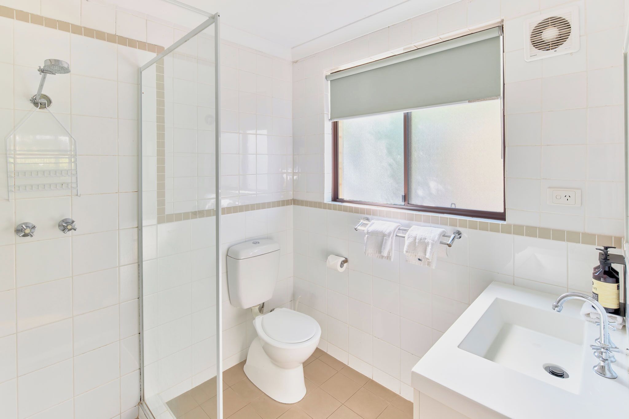 A modern bathroom with a glass shower enclosure, a toilet, a sink, and a window with a view.