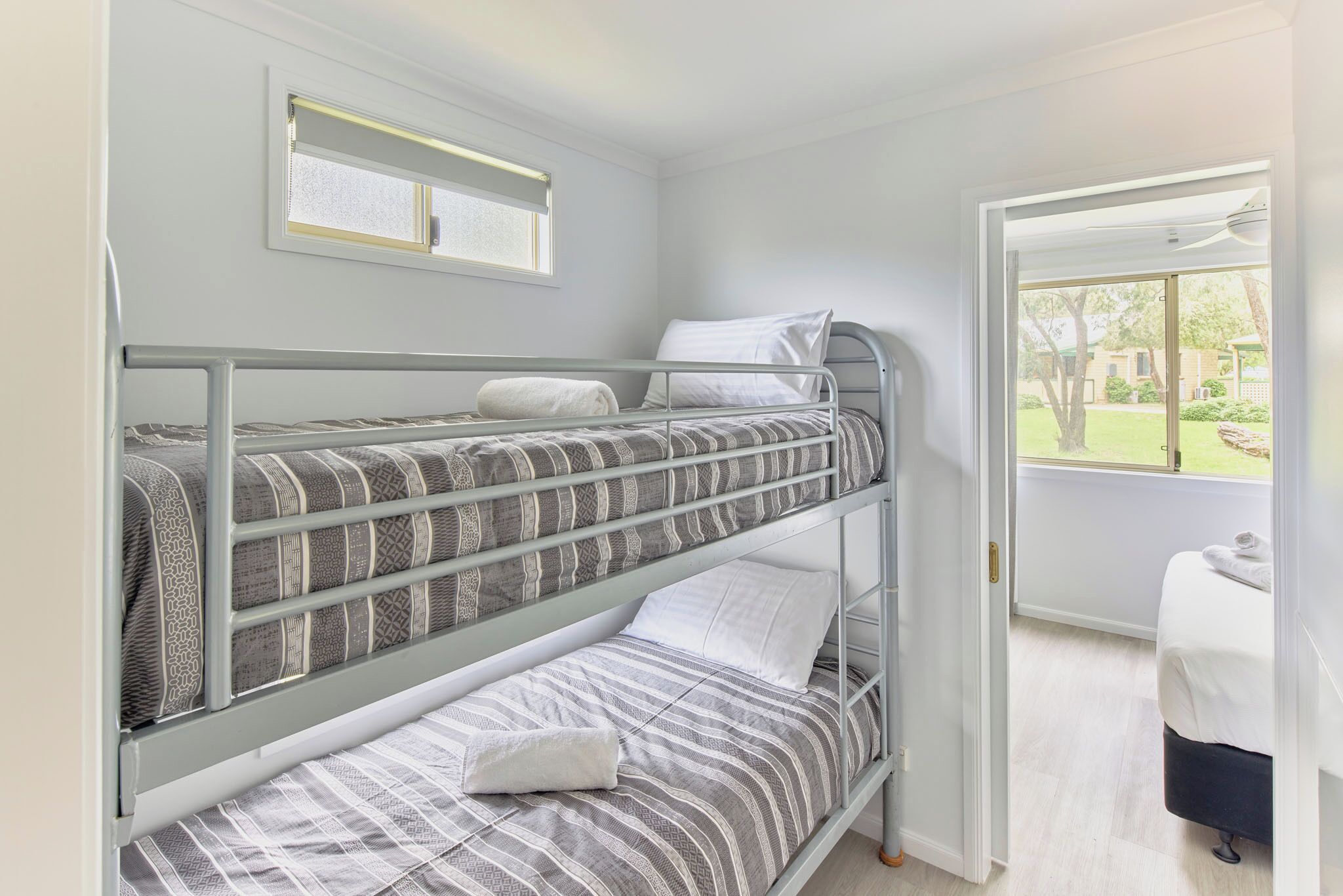 A bunk bed room with a window and a door leading to an outdoor area.