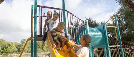 Un parque infantil con un tobogán amarillo y una estructura para escalar.